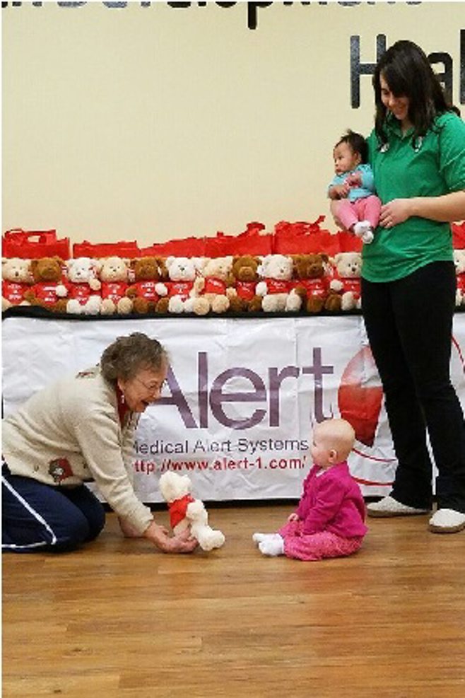 Seniors giving baby a bear to baby on floor Seniors giving baby a bear to baby on floor